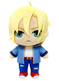 A chibi-style plush toy with short blond hair, green eyes, and an angry expression, wearing a blue jacket, white shirt, blue pants, and red shoes on a plain white background.