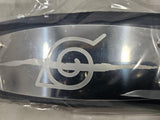 Close up of Naruto Anti Leaf Village headband metal plate engraved with Anti Leaf Village symbol and plastic packaging on grey background