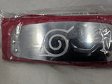 Close Up of Naruto Rock Lee red headband with metal plate engraved with Leaf Village symbol and packaged in plastic on a gray background