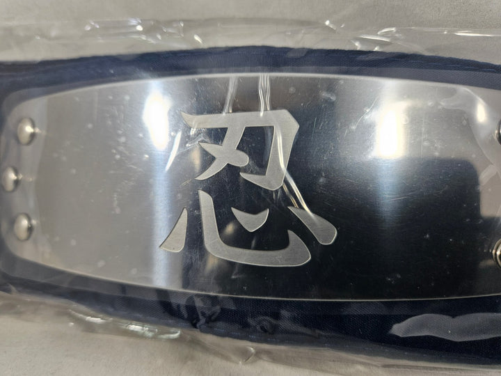 Close Up of Metallic Naruto headband with Shinobi Allied Forces engraved with Japanese kanji characters in plastic packaging on a white background