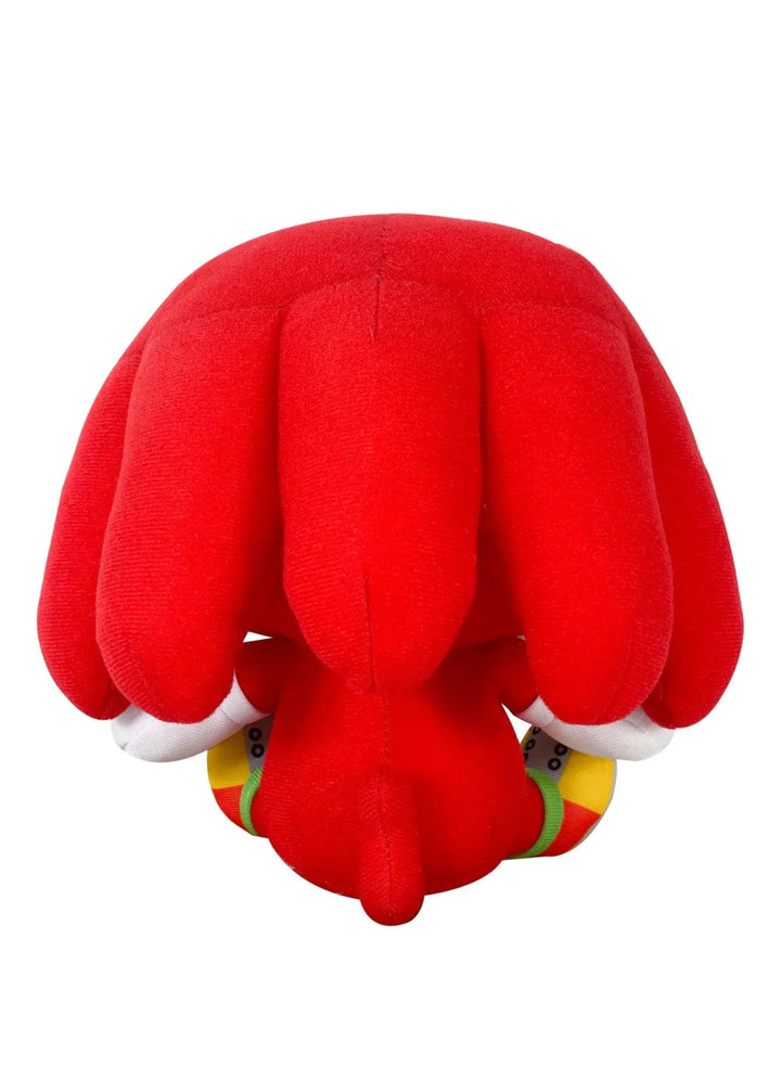 A plush toy of the character Knuckles from Sonic, shown from the back, featuring large red paws, white gloves, and colorful shoes with yellow, green, and red details, set against a plain white background.