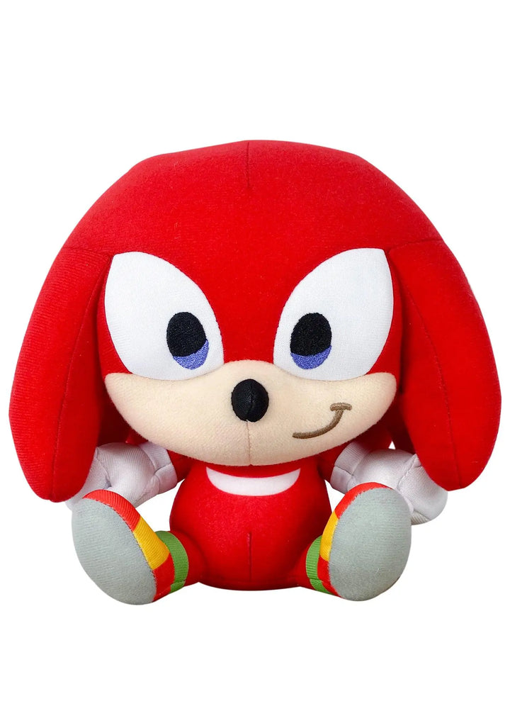 A plush toy of the character Knuckles from Sonic, featuring his signature red body, cream-colored snout and hands, and gray feet with red, yellow, and green accents, set against a plain white background.