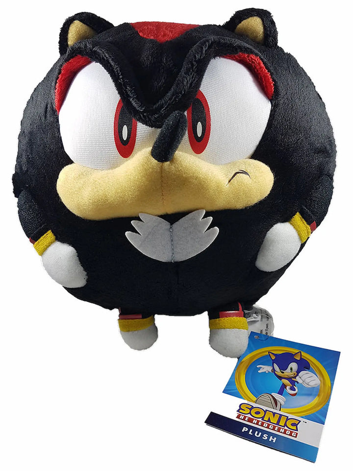 A round plush toy of Sonic's nemesis, Shadow the Hedgehog, featuring his signature black body, red eyes, yellow beak, and white paws, with a Sonic the Hedgehog tag attached.