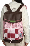 Backpack with pink geometric pattern and checkered design worn by a person in a white jacket.