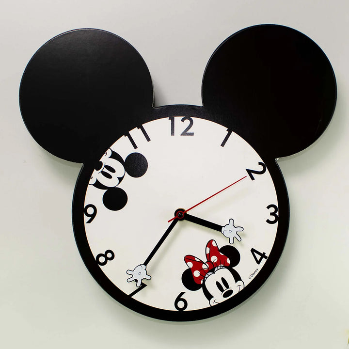 Close angle view of Mickey and Minnie Mouse Wall Clock With Ears showing Mickey ear silhouette frame decoupage clock face with Minnie Mouse in red polka dot bow peeking from lower right and Mickey glove hour and minute hands officially licensed by Disney Bioworld