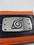 Close-up of etched silver metal Leaf Village Konoha badge on Naruto bi-fold wallet showing engraved spiral and triangle symbol with four corner rivets on black faux leather panel by Bioworld