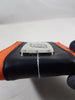 A close-up of a black leather-like wallet with an orange fabric edge and a silver metal plate featuring a stylized Naruto Hidden Leaf Village symbol, held by a dark gloved hand against a light gray background.