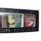 Angled close-up of Disney Nightmare Before Christmas freeze gel mini cups retail box showing Oogie Boogie cup on teal background and Zero ghost dog cup on red background with orange pumpkin detail inside black packaging window with 1.5 oz 44 ml text officially licensed by Silver Buffalo