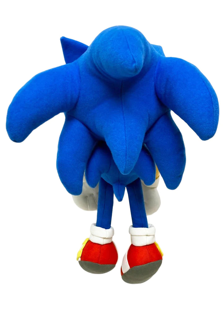 A blue plush toy with exaggerated, humorous features resembling a character, viewed from behind. It has red shoes and a playful, quirky design.
