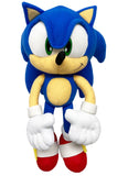 Plush toy of a blue hedgehog character with large eyes, white gloves, and red shoes, smiling with a playful expression against a plain background.